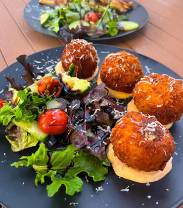 Plate of crispy fried entrées with a fresh salad, showcasing the diverse and delicious offerings on Anytime Tours’ food tours.
