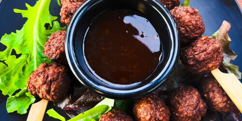 Plate of flavourful meatballs served with a dipping sauce and fresh greens, representing the delicious variety of foods you can sample on a culinary tour showcasing Mackay and Queensland cui Plate of flavourful meatballs served with a dipping sauce and fresh greens, representing the delicious variety of foods you can sample on a culinary tour showcasing Mackay and Queensland cui
