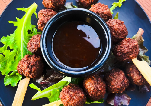 Plate of flavourful meatballs served with a dipping sauce and fresh greens, representing the delicious variety of foods you can sample on a culinary tour showcasing Mackay and Queensland cui Plate of flavourful meatballs served with a dipping sauce and fresh greens, representing the delicious variety of foods you can sample on a culinary tour showcasing Mackay and Queensland cui