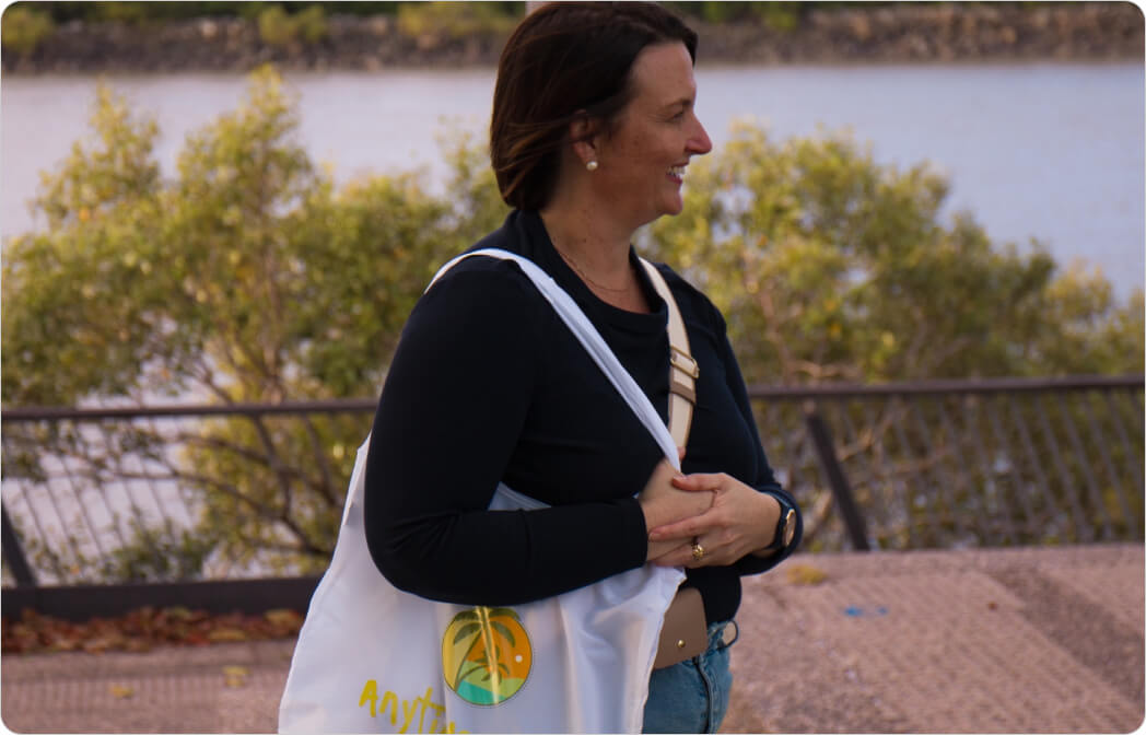 Smiling woman with an Anytime Tours bag enjoying the scenic waterfront, highlighting the delightful experiences on the Mackay Harbour Food Tour. Smiling woman with an Anytime Tours bag enjoying the scenic waterfront, highlighting the delightful experiences on the Mackay Harbour Food Tour.